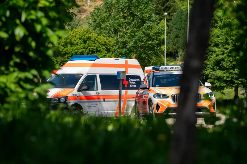 Rettungswagen und Einsatzfahrzeug des DRK zwischen Bäumen