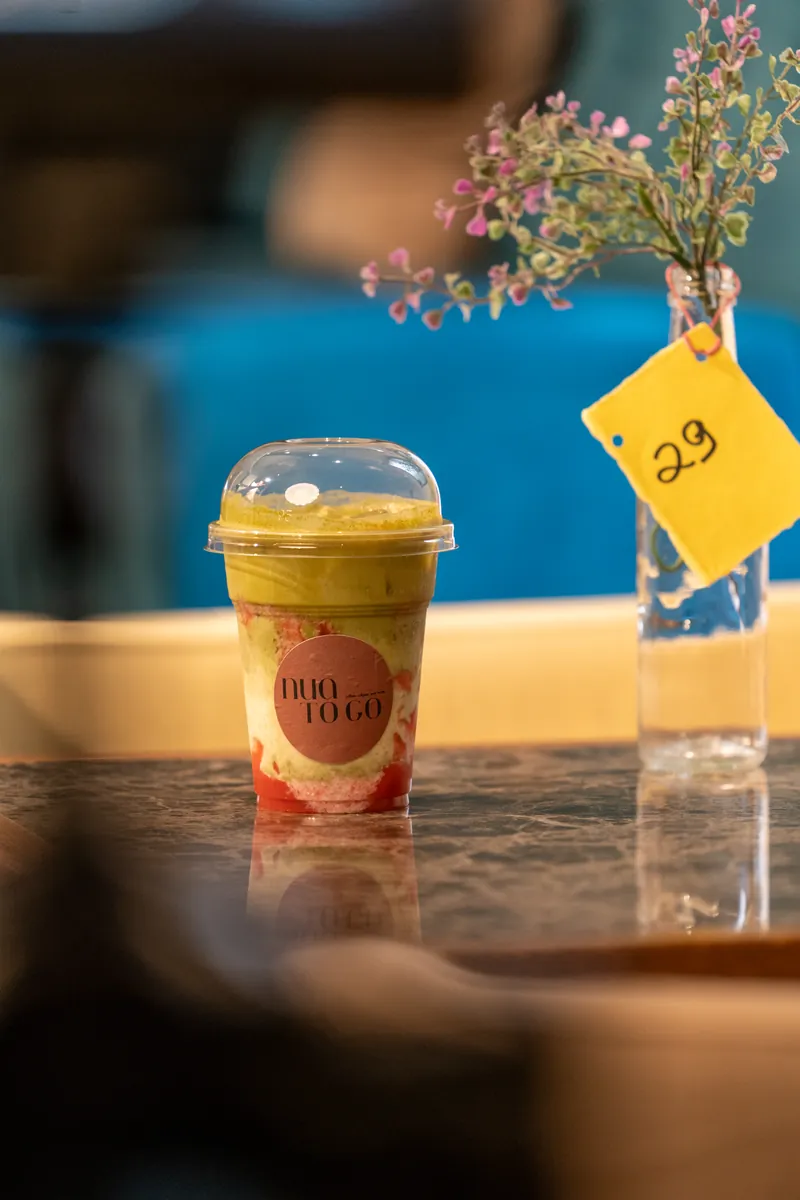 Smoothie im Becher auf einem Tisch, daneben Blumen