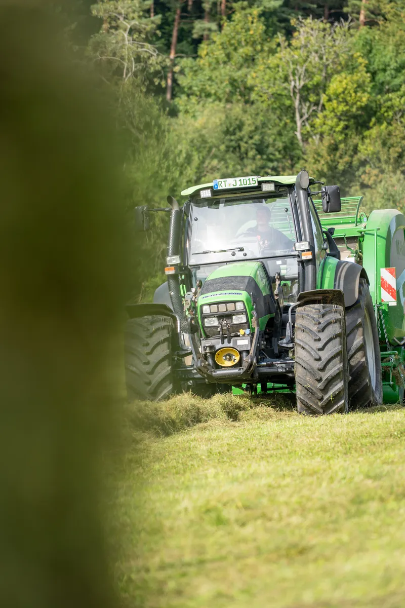 Traktor mit Ballenpresse hinter unscharfem Gras