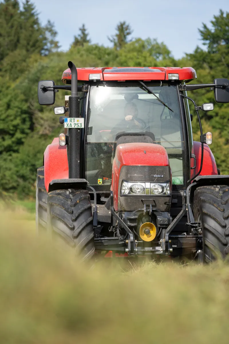 Roter Traktor frontal hinter Heu