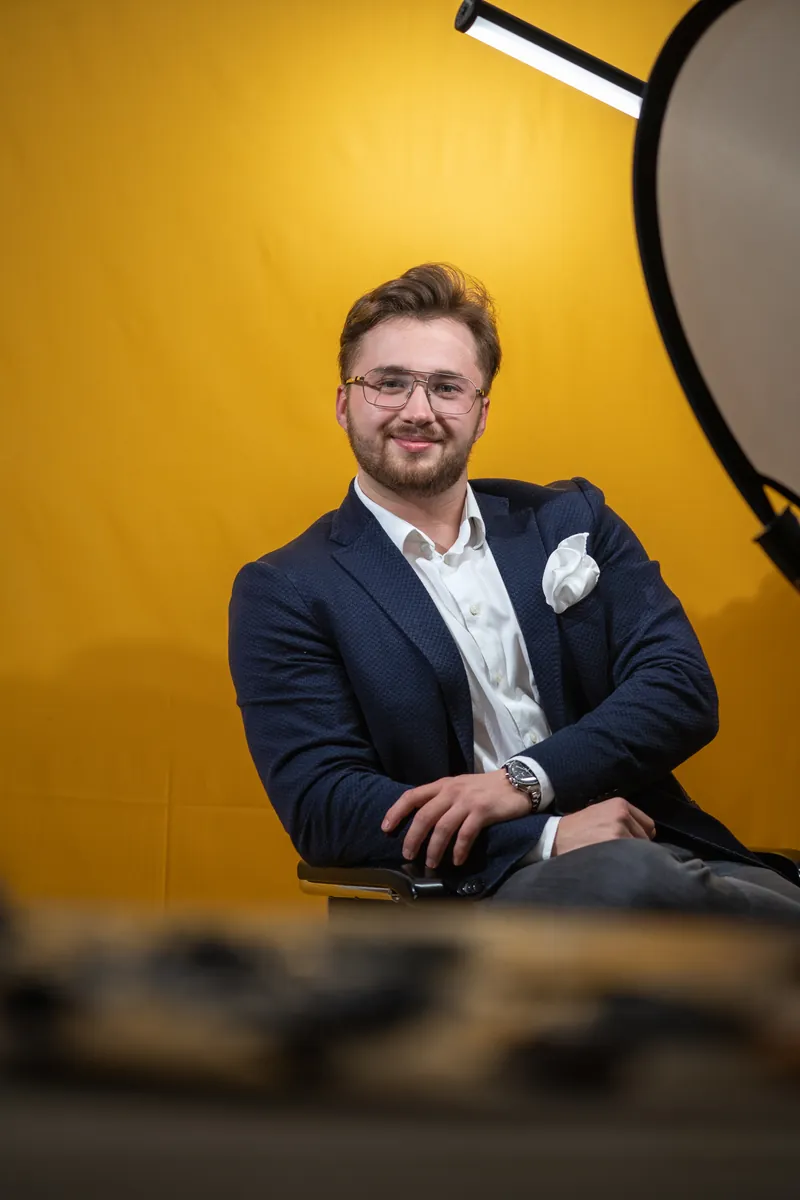 Porträt eines Mannes im Sakko vor gelbem Hintergrund